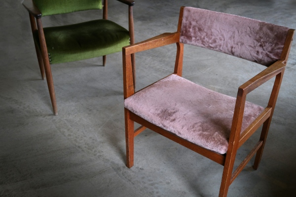 Twee vintage stoelen, een groene en een roze, geplaatst op een moderne betonvloer